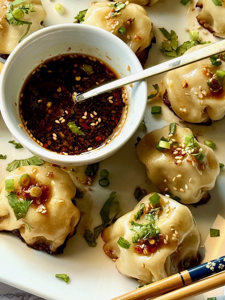 Chicken dumplings with a small bowl of dipping sauce.