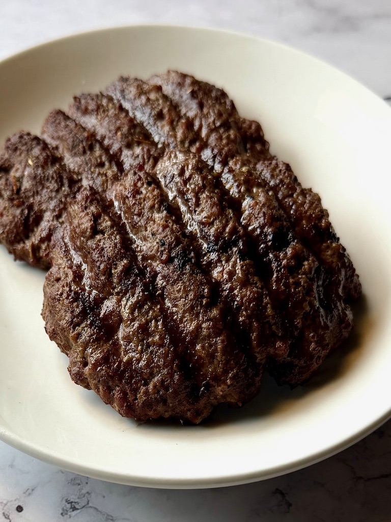 Burger patties grilled on a plate.
