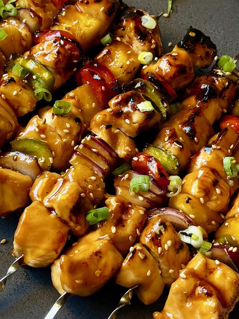 Grilled teriyaki chicken kabobs on a serving plate.