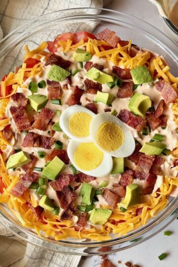 Top view of the layered salad with hard boiled egg, crispy bacon, and avocado.