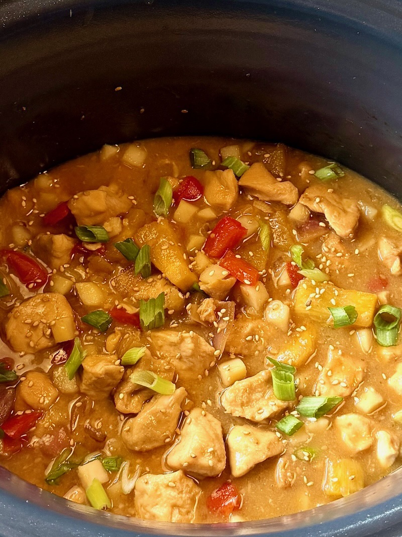 Slow cooker pineapple chicken topped with green onions and sesame seeds. 