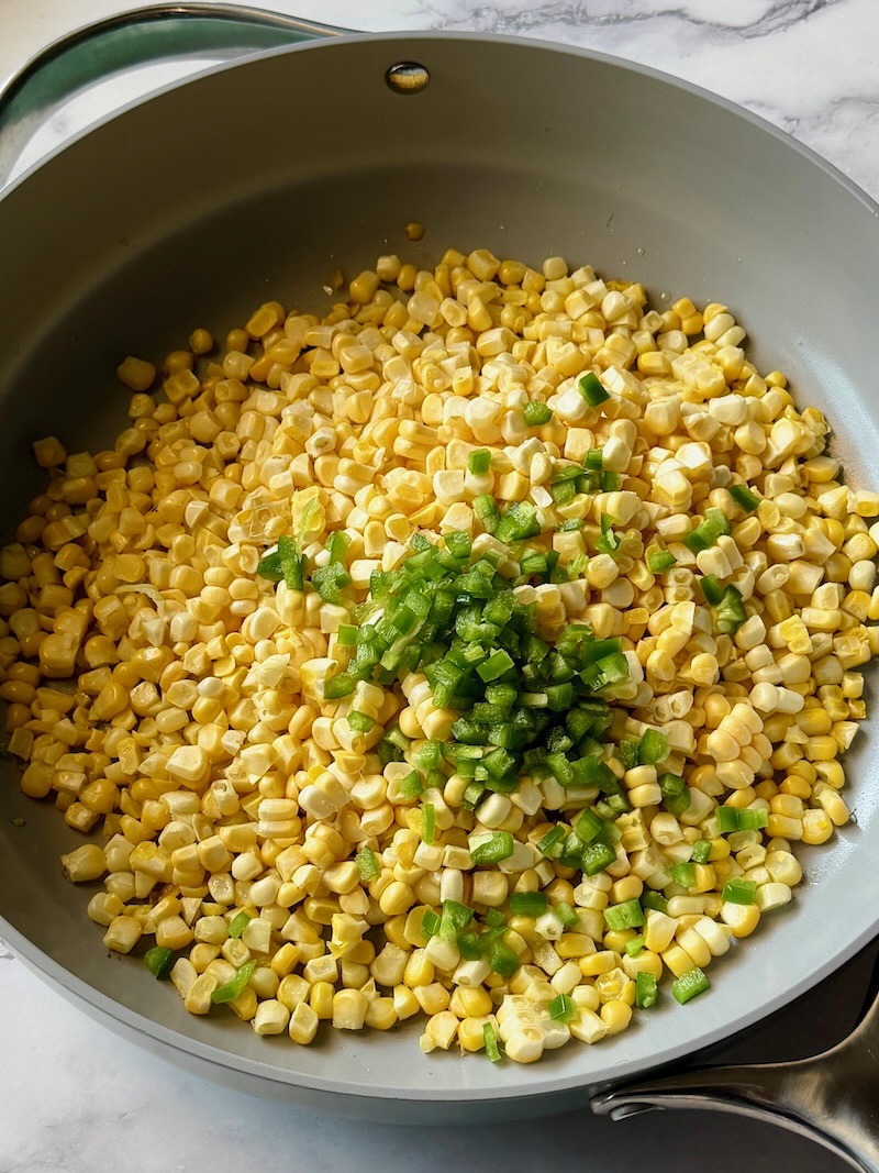 Corn and jalapeños in a skillet with olive oil