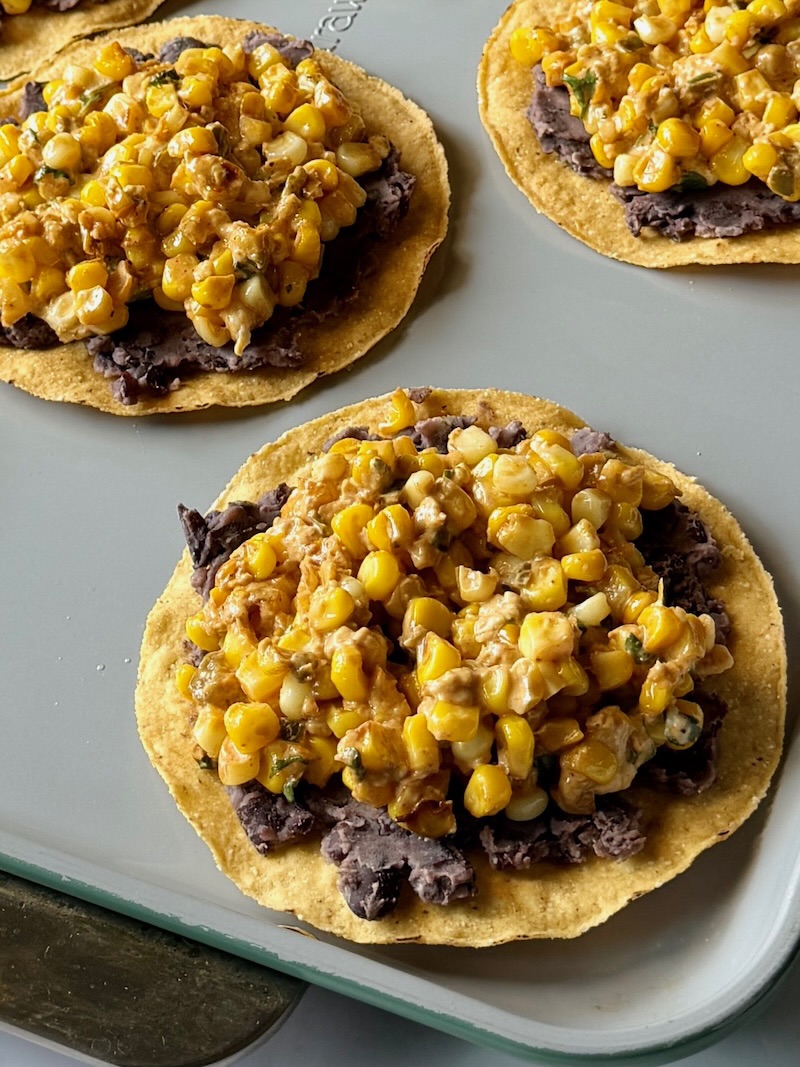 Corn mixture on top of the black beans on tostadas.