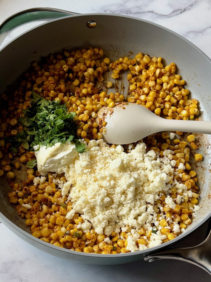 Sour cream, mayo, cilantro, and spices added to the corn in the skillet. 