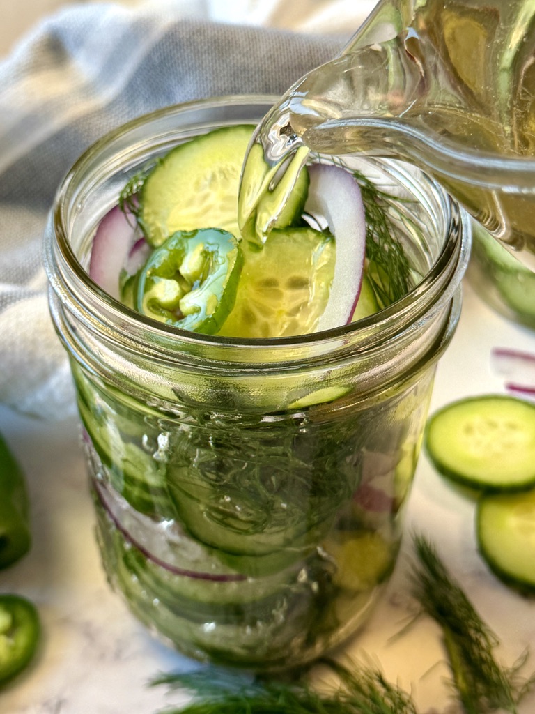 vinegar liquid pouring over cucumbers