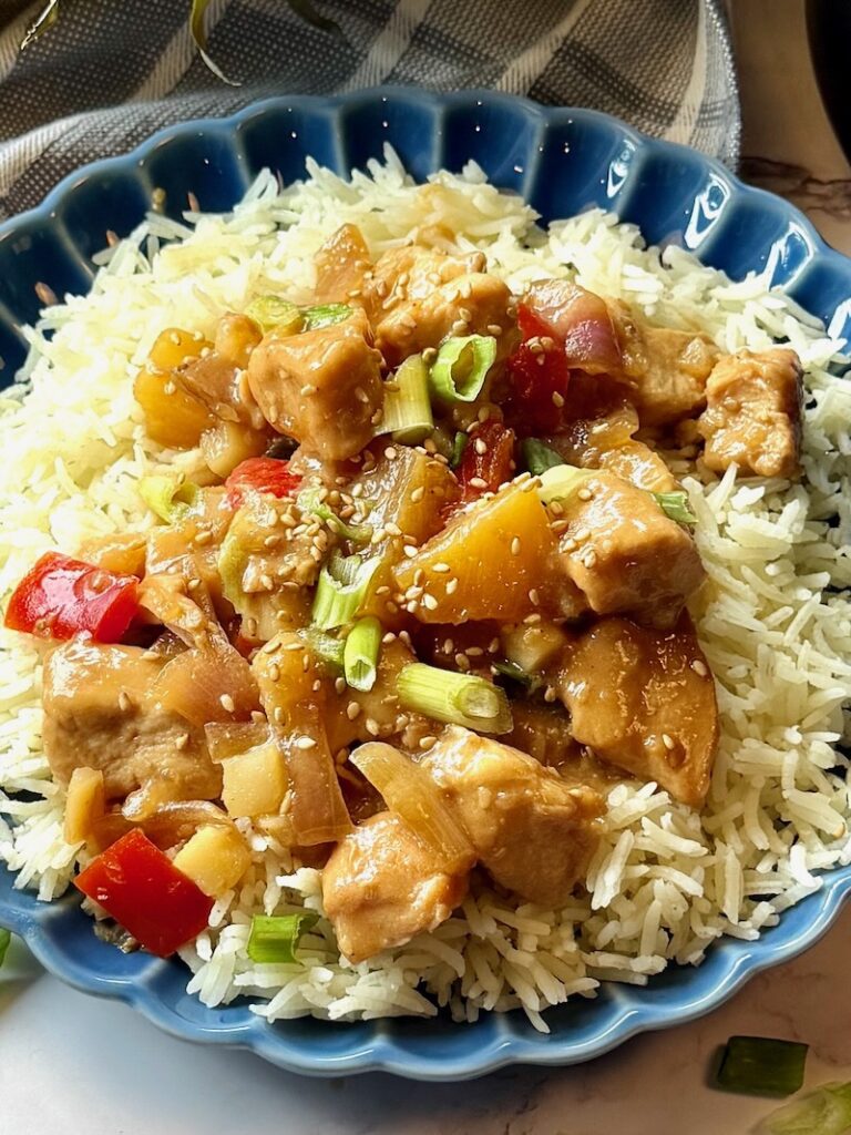 Pineapple chicken over rice and served on a plate.