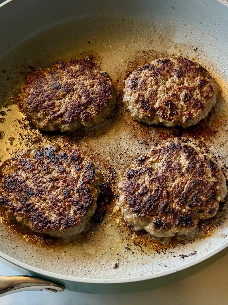 Burger patties cooked in a skillet. 