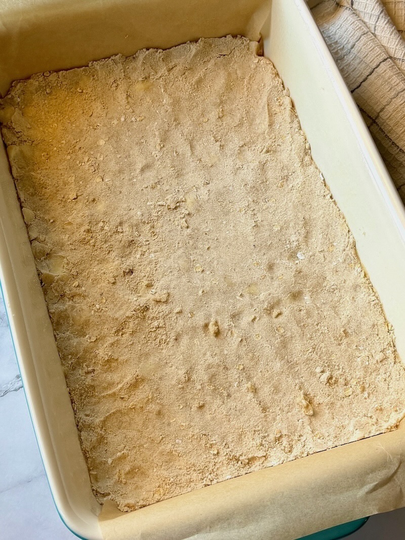Crust pressed in a baking pan in an even layer on top of parchment paper.