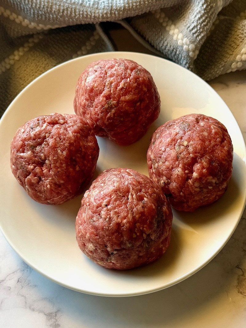 Ground beef mixture formed into 4 balls.