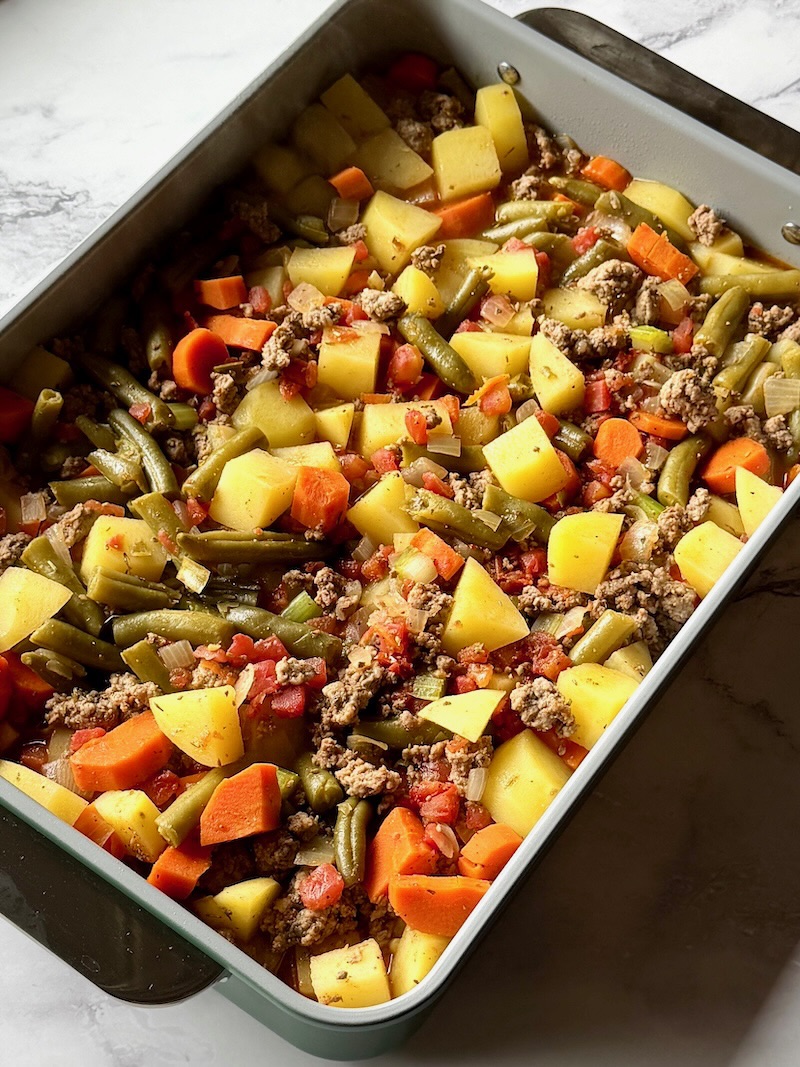 Ground beef and vegetables added to a baking dish