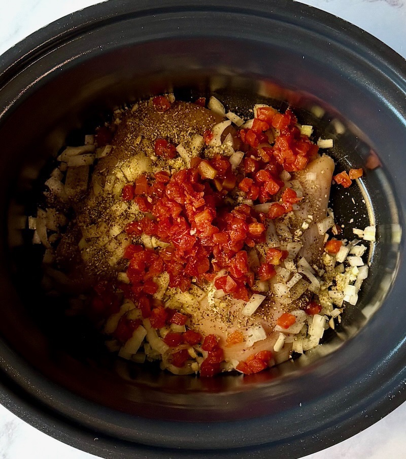chicken, onions, garlic, tomatoes, seasonings, and chicken broth in the slow cooker.