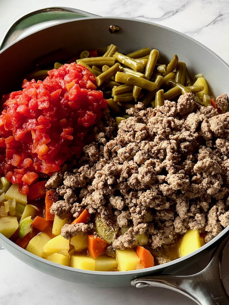 ground beef, tomatoes, seasonings and broth added to the vegetables. 